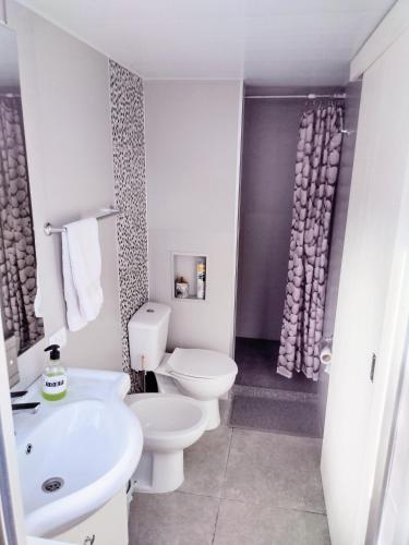 a white bathroom with a toilet and a sink at Colonia in Colonia del Sacramento