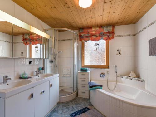 uma casa de banho com uma banheira, um lavatório e um chuveiro em Bei Hanni em Söll