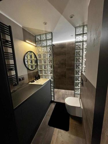 a bathroom with a toilet and a clock on the wall at HELLO Apartamenty - Pinia blisko Aquaparku in Karpacz