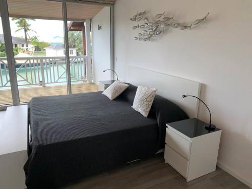 a bedroom with a black bed and a balcony at Luxury Waterfront Villa 249C South Beach in Jolly Harbour