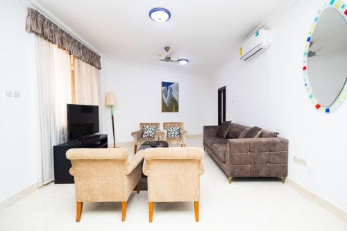 Stay Play Away Residences - 3 bed, Airport Residential, Accra في آكرا: غرفة معيشة مع أريكة وطاولة وكراسي