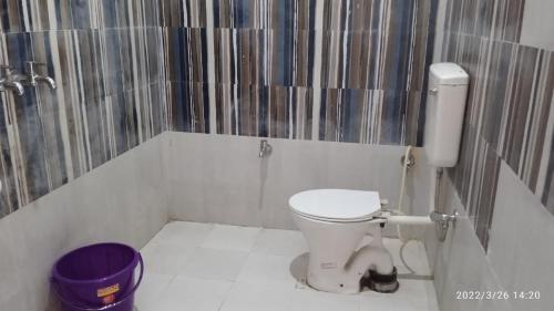 a bathroom with a white toilet and a purple bucket at Dharmshala in Badrīnāth