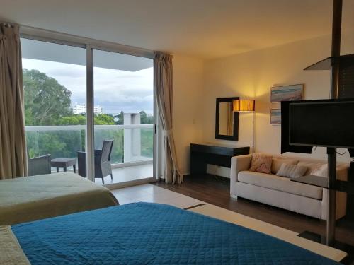 Habitación de hotel con sofá y ventana grande. en Playa Blanca Town Center Suites, en Río Hato