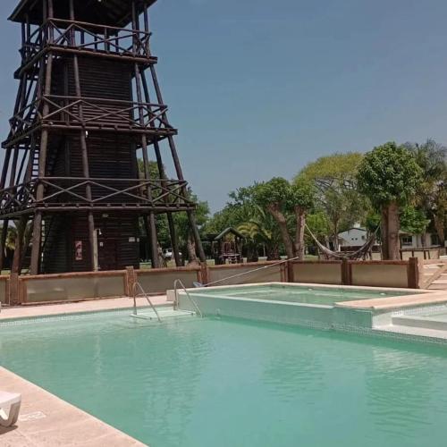 ein Schwimmbad mit Wasserturm im Hintergrund in der Unterkunft Cabañas El Mangrullo de Obligado in Vuelta de Obligado