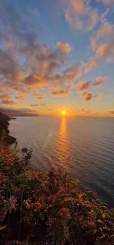 a sunset over a body of water with the sun setting at Villa Alta Vista in São Jorge