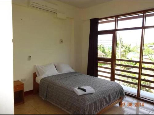a bedroom with a bed and a large window at Hostal El Puerto in Yurimaguas