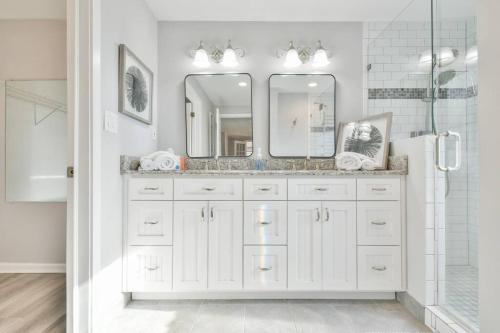 Baño blanco con lavabo y espejo en Tranquil Lakeside Getaway with Modern Comfort, en Flowery Branch