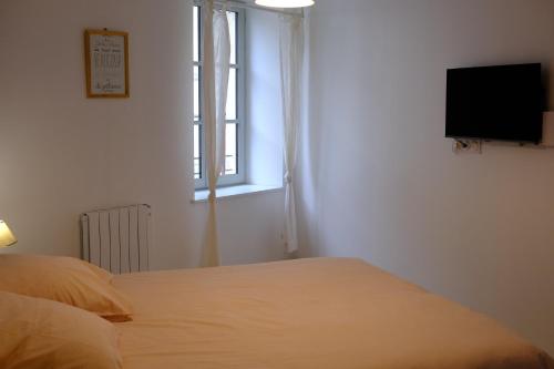 een slaapkamer met een bed en een televisie aan de muur bij ON LOGE A PIED ET A CHEVAL in Jonzac