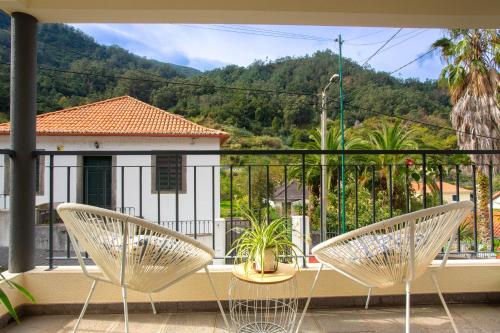 two chairs on a balcony with a view of a house at A Casa da Tia in São Vicente