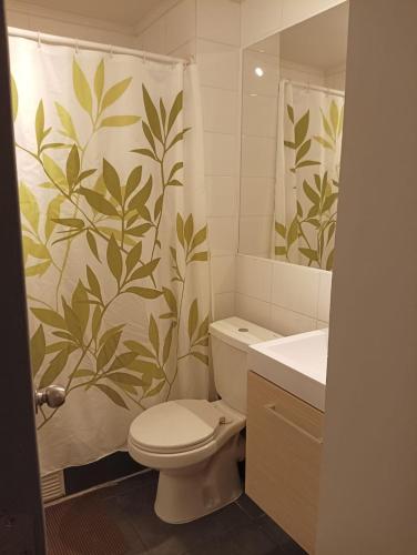 uma casa de banho com um WC e uma cortina de chuveiro com folhas em Departamento la herradura frente al mar em Coquimbo