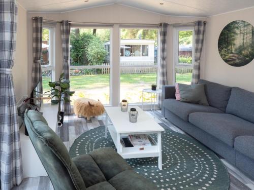 sala de estar con sofá y mesa en Luxury chalet on cozy family campsite. en Garderen