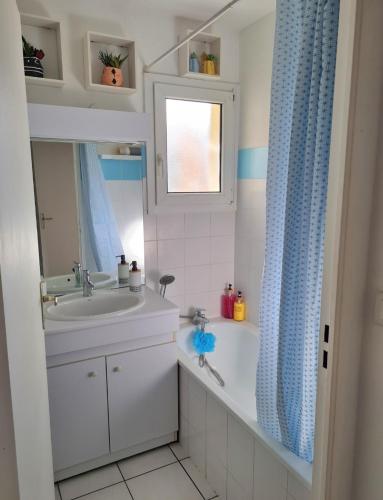une salle de bain avec un lavabo et un rideau de douche dans l'établissement Logement agréable proche Bordeaux, à Pont-de-la-Maye