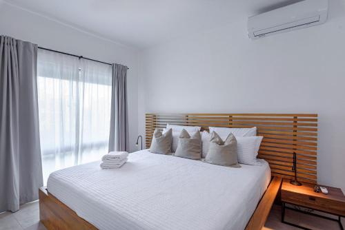 1 dormitorio con 1 cama con sábanas blancas y ventana en Apartamento 2 habitaciones piscina cerca de playa, en Punta Cana