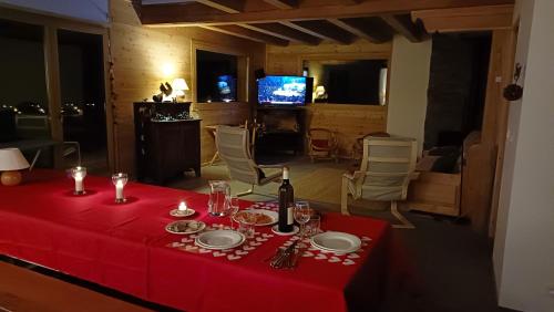 un tavolo con una tovaglia rossa e una bottiglia di vino di Les Cabris a Pelvoux