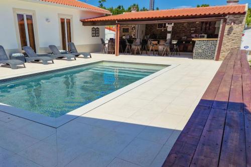 a swimming pool with chairs and a house at La Casa De Lylou location de bungalows in Lavos
