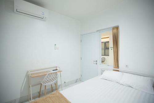 Habitación blanca con cama y escritorio en My Stay Semarang, en Candi