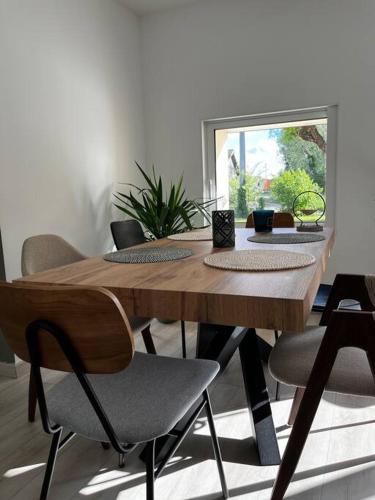 - une table en bois avec des chaises dans une chambre avec une fenêtre dans l'établissement Petit cocon au cœur du médoc, à Saint-Estèphe