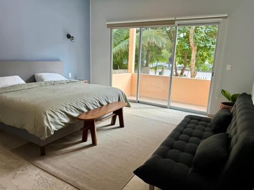 um quarto com uma cama, um sofá e uma janela grande em Sasay em Puerto Aventuras