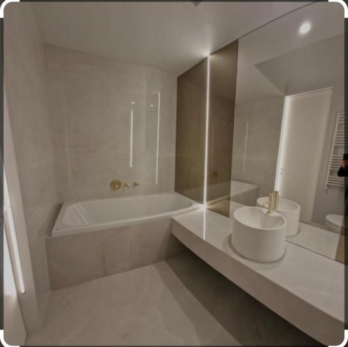 La salle de bains blanche est pourvue d'une baignoire et d'un lavabo. dans l'établissement Luxury Wellness&Spa, à Bucarest