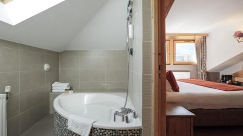 a bathroom with a bath tub and a bed at Les Gourmets - Chalet Hotel in Chamonix-Mont-Blanc