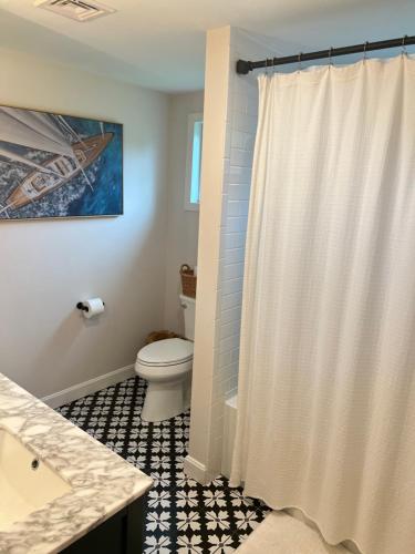 y baño con aseo y cortina de ducha. en Modern Family Home in Middletown, RI- just 4 mi to Newport!, en Middletown