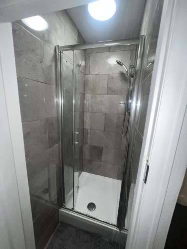 een douchecabine met een glazen deur in de badkamer bij House Parking Contractors in Leicester