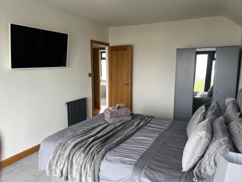 a bedroom with a large bed with a flat screen tv at Broadway Beach Home with Hot tub in Herne Bay