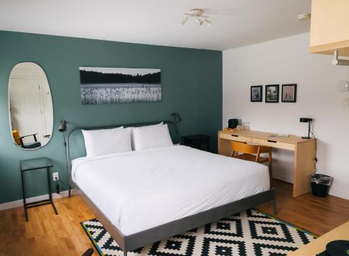 a bedroom with a white bed and a desk at Beatnik Hotel in Bromont