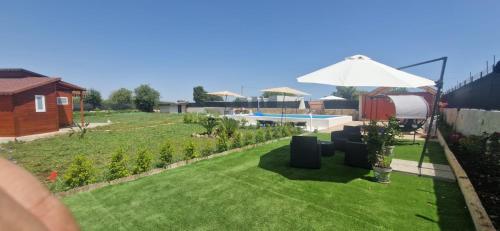 un jardín con sombrilla y piscina en UGVilla, en Arenella