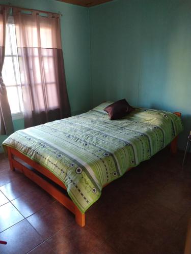 Una cama en una habitación verde con una manta. en Relax Serrano en Santa María