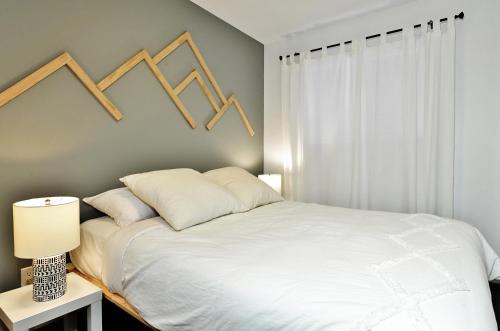a bedroom with a white bed and a window at Condo 305 33 Chemin du Hameau by Les Chalets Alpins in Stoneham