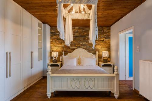 um quarto com uma cama branca e uma parede de tijolos em Efharis Beachfront Villa em Platamon