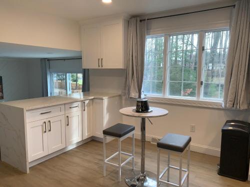 uma cozinha com armários brancos, uma mesa e bancos em SPAC Trac Oasis em Saratoga Springs