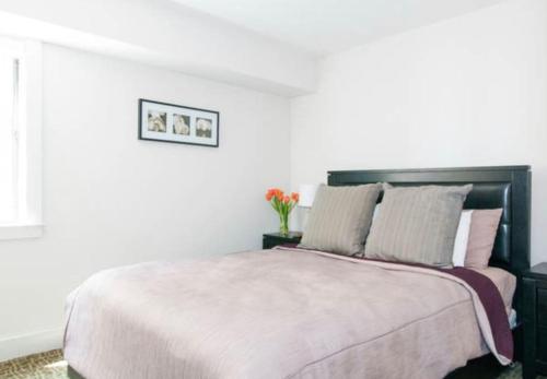 a white bedroom with a large bed with pink pillows at Beautiful Downtown & Bay Bridge, Vineyard Views! in San Francisco