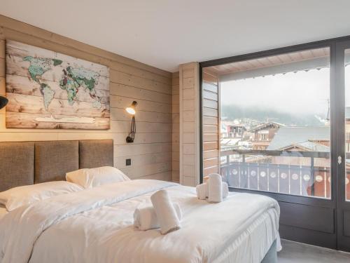 une chambre avec un grand lit blanc et une fenêtre dans l'établissement Joli 3 pièces rénové en centre-ville de Morzine avec balcon et parking - FR-1-754-21, à Morzine