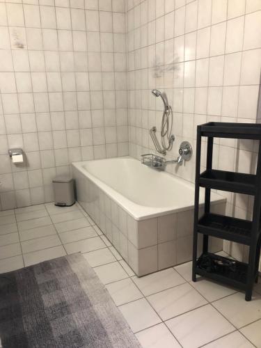 Baño blanco con bañera y estante negro en Ferienwohnung Zum Dütetal OG Apartment 1 en Hilter am Teutoburger Wald