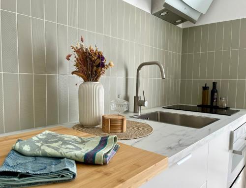 une cuisine avec un évier et un vase de fleurs sur un comptoir dans l'établissement La maison du douanier. Un balcon au soleil, à Antibes