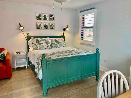 Una cama verde en un dormitorio con ventana. en Ocean view studio with heated pool, en St Pete Beach