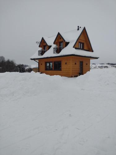 a house with a snow covered roof in the snow at Góralski Domek Tomek in Ciche