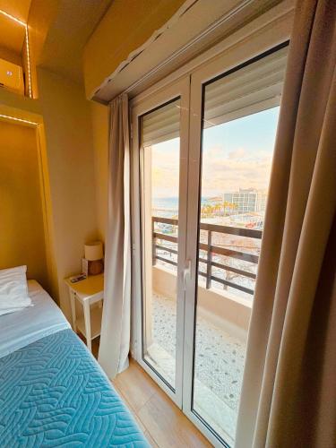 1 dormitorio con 1 cama y balcón con vistas. en Blue Horizon Gem On The Port, en Rafina