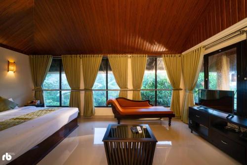 um quarto com uma cama, uma cadeira e janelas em Le Kuruva isles wayanad jungle resort em Chegāt