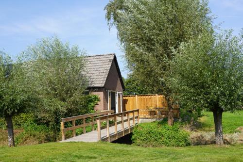 a small house with a wooden bridge in front of it at De Knotwilg in Loon op Zand