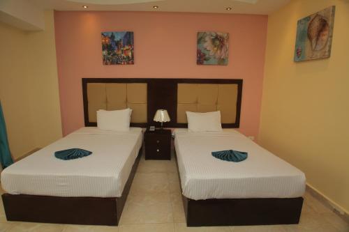two beds in a hotel room with two beds at LUSINDA HOTEL MANAGEMENT BY ZAD in Suez