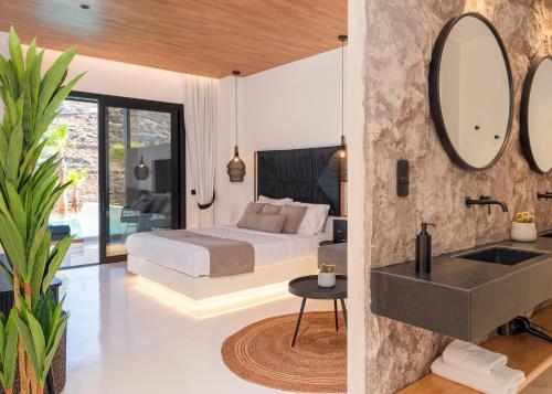 a bedroom with a bed and a sink and a mirror at Ftelia Black Villas in Elia