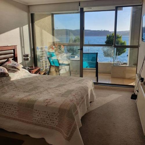 1 dormitorio con cama y vistas al agua en Departamento en Condominio privado Costa Pingueral, en Concepción