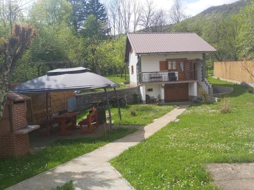 a house with a table and a tent in the yard at Kuća za odmor Denis in Mala Lešnica