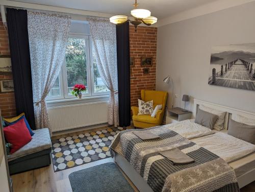 a bedroom with a bed and a chair and a window at Várfal apartman in Kőszeg