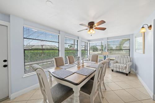 a dining room with a table and chairs and windows at Downtown Cottage - Walk to the Beach & Restaurants in Cocoa Beach