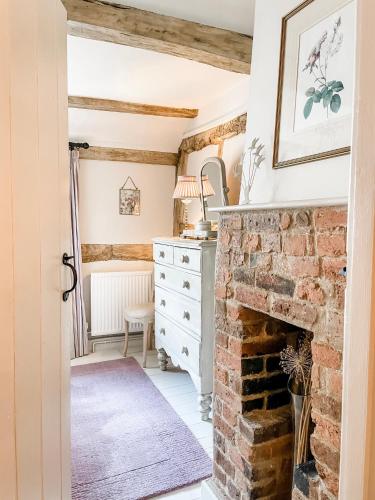 a living room with a brick fireplace and a dresser at Charlie's Cottage in Ludlow