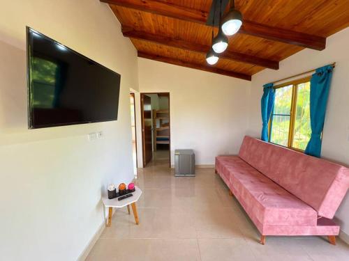 a living room with a red couch and a flat screen tv at Finca Villa Sophia! in Quimbaya